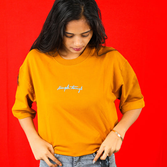 Person wearing a mustard yellow t-shirt with text on a red background